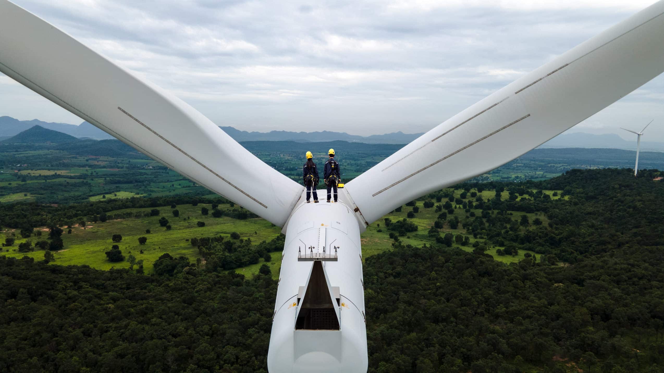 Men standing on wind turbine